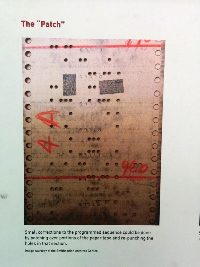 A physical punch card repaired with tape patching over accidentally punched holes.